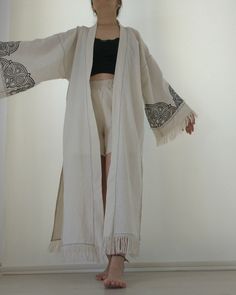 Embrace your bohemian  spirit with our Handmade Boho Kimono, featuring beautiful fringe details and intricate mandala designs. This unique open front cardigan is perfect for layering over your favorite outfits, adding a touch of elegance and artistic flair. Crafted with care, this kimono combines comfort with style, making it an essential piece for any boho-chic wardrobe. Features: *Intricate Mandala Design: Handcrafted with detailed mandala patterns on the sleeves and back, adding a unique artistic touch. *Fringe Details: Elegant fringe along the hem and sleeves enhances the bohemian vibe and adds movement to your look. *High-Quality Fabric: Made from soft, durable fabric for ultimate comfort and long-lasting wear. *Versatile Fit: Open front design allows for easy layering, suitable for v Bohemian Long Sleeve Kimono With Fringe, Festival Long Sleeve Kimono With Fringe, Long Sleeve Festival Kimono With Fringe, Long Sleeve Fringe Kimono For Festivals, Bohemian Fringe Cardigan For Festivals, Bohemian Beige Kimono For Festival, Bohemian Fringe Kimono For Festival, Bohemian Long Kimono With Tassels, Bohemian Fringe Kimono For The Beach