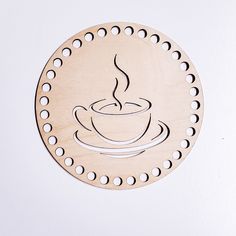 a wooden coaster that has a coffee cup on it with holes in the middle and an embossed design