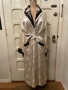 Beautiful, elegant satin robe from the 1950s. Hand-embroidered with a velvet collar and cuffs. Delicate floral designs. Ivory white coloring *Quality note* Small tear on the seam (picture included) MEASUREMENTS Sleeve: 22in Bust: 42in Shoulder: 19in Length: 52in