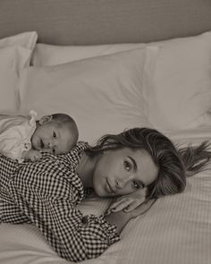 a woman laying on top of a bed holding a baby