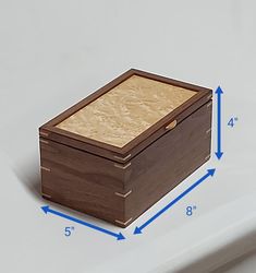 a wooden box sitting on top of a white counter next to a blue measuring tape