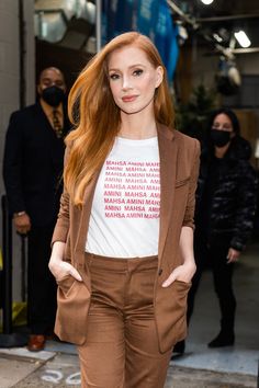 a woman with long red hair wearing brown pants and a t - shirt