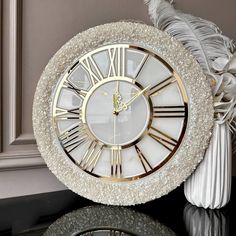 a white clock sitting on top of a table next to a vase filled with flowers