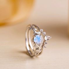 a ring with an opal stone and leaves on the side, sitting on a table