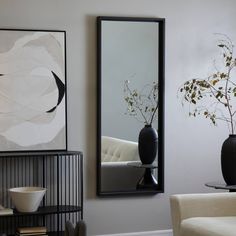 a living room filled with furniture and a large mirror on the wall next to a coffee table