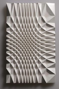 an abstract sculpture made out of white paper on a gray wall with no one in it