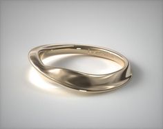 a gold wedding ring with curved edges on a white background, close - up view