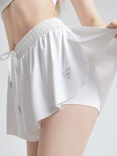 a woman in white shorts with her hand on her hip and the bottom of her panties