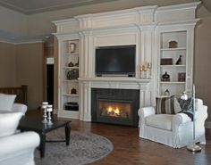 a living room filled with furniture and a flat screen tv mounted on the wall above a fire place