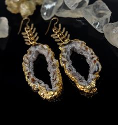 "Introducing the stunning Oco Agate Geode Slice Earrings - the perfect accessory to elevate any outfit and bring a touch of natural beauty to your look. These earrings feature unique agate slices with swirling patterns of browns, greys, and whites, and a sparkling druse of crystals at the center. The agate is beautifully framed in gold, adding a touch of luxury. The earrings hang from a striking, long fishbone-style gold-plated chain, making them the perfect statement piece. Not only are they a Crystal Statement Earrings, Agate Slices, Geode Slice, Chain Making, Silver Paper, Gold Bond, Druzy Earrings, Agate Geode, Fish Bone