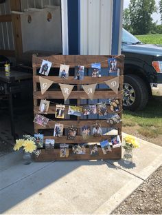 a wooden pallet with pictures hanging on it and flowers in front of the house