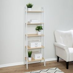 a white chair sitting next to a shelf filled with boxes and plants on top of it