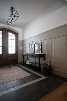 a room with a rug, vase and mirror on the floor next to a door