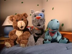 three stuffed animals sitting on top of a bed