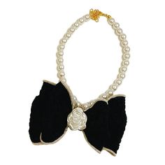 a black and white necklace with pearls on it's sides, featuring a rose brooch