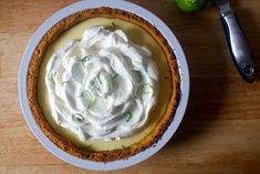 a pie with whipped cream on top sitting on a table next to a knife and fork