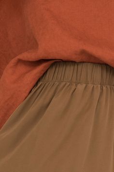 the bottom half of a bed with an orange comforter and brown sheets on it