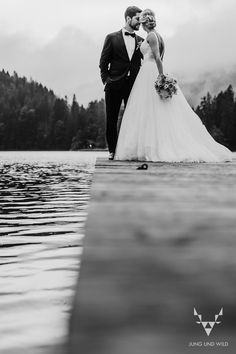 a bride and groom are standing on the dock