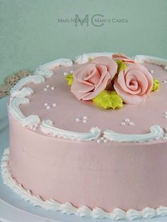 there is a pink cake with two roses on the top and white trimmings