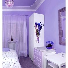 a bedroom with purple walls and furniture in the room, including a white desk and dresser