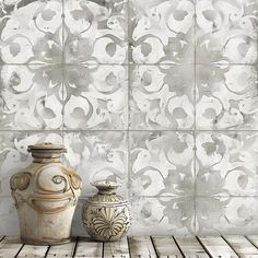 two vases sitting next to each other in front of a wall with decorative tiles on it