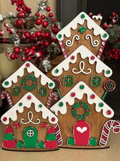 three decorated gingerbread houses sitting on top of a table next to a christmas tree