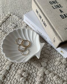 two wedding rings are on a plate next to a stack of books and a book