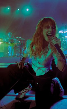 a woman sitting on the ground with her mouth open and holding a microphone in front of her