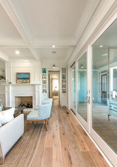 a living room with wood floors and white furniture in front of glass doors that lead to an outdoor patio