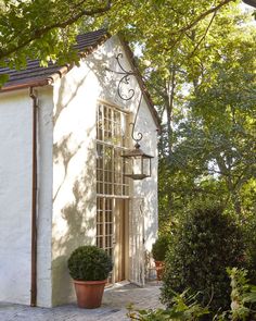 a white house with a potted plant in front of it and trees surrounding the building