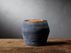 a blue vase sitting on top of a wooden table next to a lit candle in it