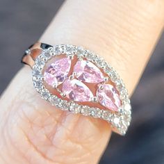 a woman's hand with a pink diamond ring on top of her finger,