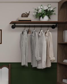 a shelf with clothes hanging on it and a vase filled with flowers next to it