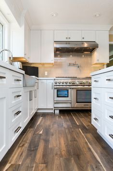 a kitchen with white cabinets and wood flooring, including an oven and stove top