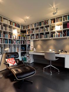 the room is full of books and has a leather chair in front of an office desk