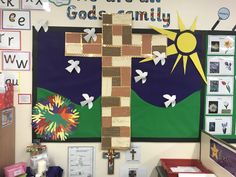 a bulletin board with a cross hanging from it's side and pictures on the wall