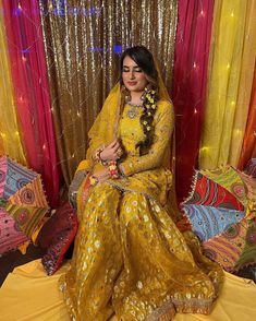 a woman sitting on top of a bed in a yellow dress