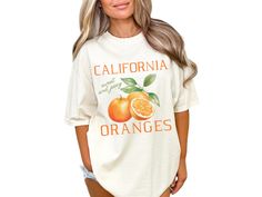 Embrace your love for nature and gardening with our vintage style "California Oranges" shirt, adorned with oranges. This short-sleeved crewneck tee is perfect for any citrus lover, farmer, plant lover, or gardener, adding a touch of cottagecore aesthetic to your wardrobe. COMFORT COLORS 1717 SHIRT: Unisex 100% US cotton - ethically grown and harvested Pre-Shrunk Fabric Relaxed Fit - Size up for a trendy oversized look Seamless Sides Double Needle Stitching Garment-dyed  CARE INSTRUCTIONS: Wash i Vintage Cotton Tops With Fruit Print, Vintage Fruit Print Crew Neck Tops, Vintage Summer Top With Fruit Print, Vintage Fruit Print Top For Summer, Vintage Crew Neck Tops With Fruit Print, Cottagecore Printed T-shirt With Relaxed Fit, Orange Screen Print Tops For Spring, Spring Orange Screen Print Tops, Casual Orange Fruit Print Top