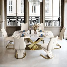 a dining room table with white chairs and a chandelier