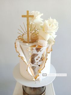 a white cake with gold decoration and flowers on top