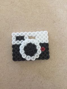 a black and white sheep made out of legos on the floor with buttons attached to it