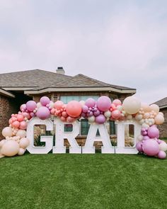 a large balloon arch that says grad in front of a house