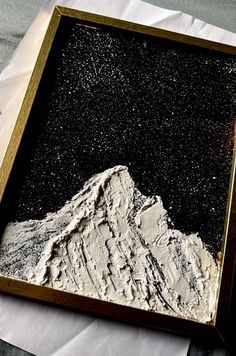 a piece of art that looks like a mountain is in a frame on the table