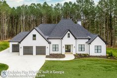 a large white house in the middle of a wooded area with lots of trees around it