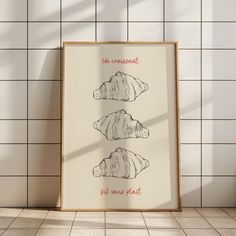 three seashells are shown on a white tile wall next to a framed poster