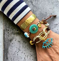 Elevate your accessory game with this stunning boho chic bracelet set. Featuring a blend of turquoise and gold tones, this set includes a handmade adjustable cord bracelet adorned with turquoise donuts and evil eye charms, paired with a hammered brass cuff. Perfect for adding a touch of bohemian elegance to any outfit. Ideal for summer fashion, festival wear, and unique gift ideas for her. Hippie Green Bracelet Jewelry, Bohemian Resizable Bangle Bracelets, Handmade Turquoise Wrap Bracelet, Turquoise Hand Wrapped Bracelets For Festivals, Turquoise Bohemian Wrap Bracelet, Hippie Turquoise Bracelets For Festival, Hippie Gold Bracelet, Bohemian Resizable Bangle Cuff Bracelet, Turquoise Hand Wrapped Jewelry For Festivals