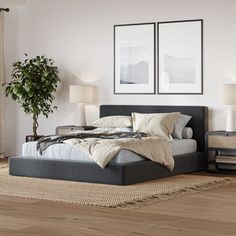 a large bed sitting on top of a wooden floor next to two pictures above it