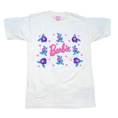 a white t - shirt with pink and blue flowers on the front, says barbie