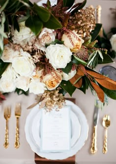 the table is set with white and gold flowers