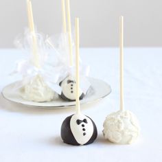 cake pops with white frosting and black candies on them sitting on a plate